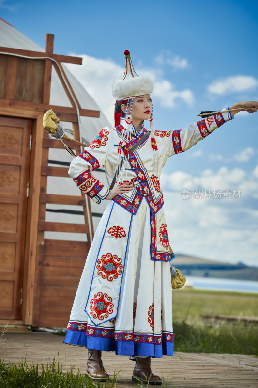 草原湖畔身穿蒙古族饰手持弓箭的蒙族少女
