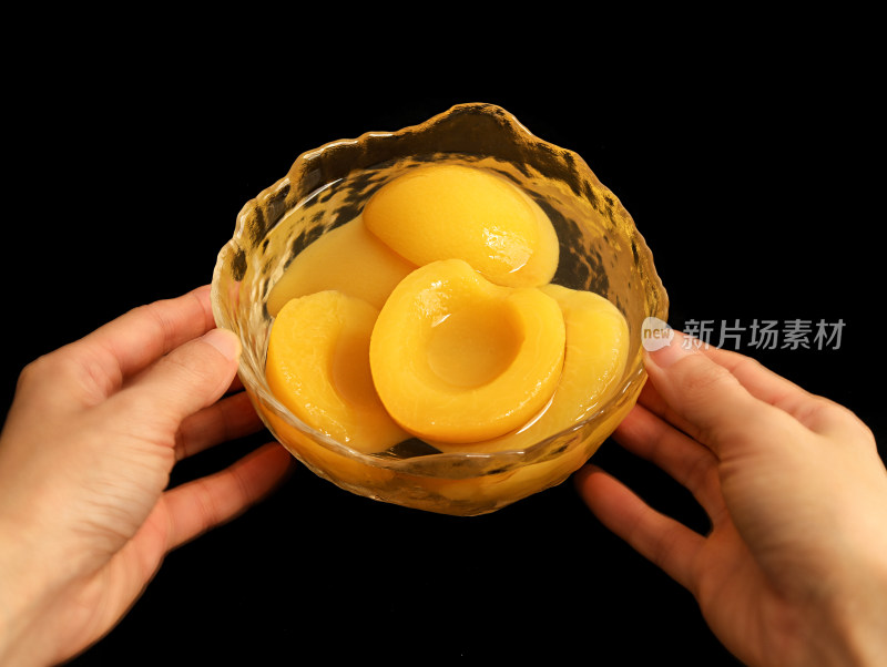 黑色背景，碗中装着的美食黄桃罐头