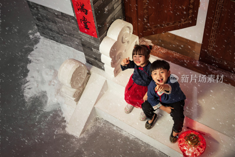 坐在门口台阶上看雪花的男孩女孩