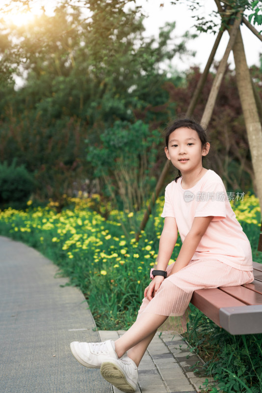 夏天夕阳下坐在公园长椅上的中国女孩