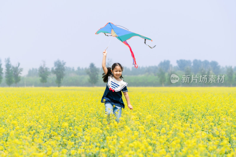 夏天拿着风车在油菜花田中奔跑的女孩