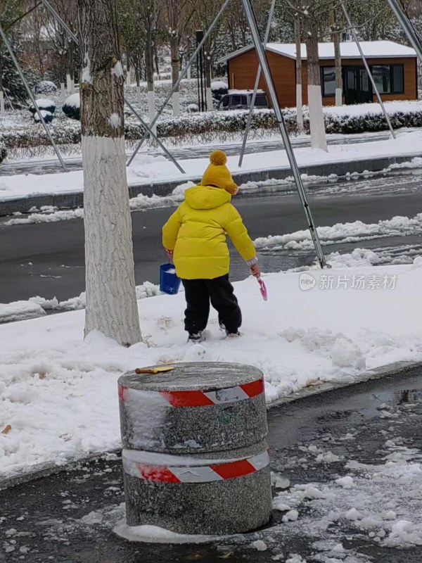 穿黄色外套的小孩在户外玩雪