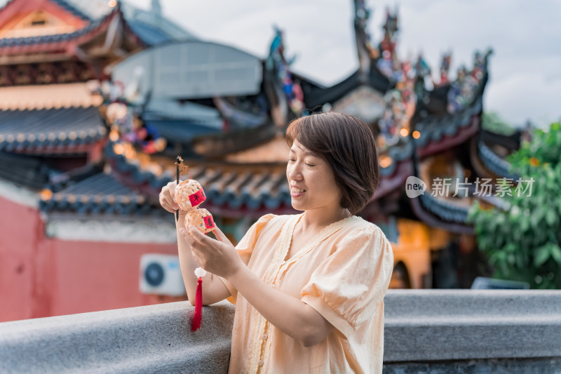 女子手持灯笼站在古建筑旁