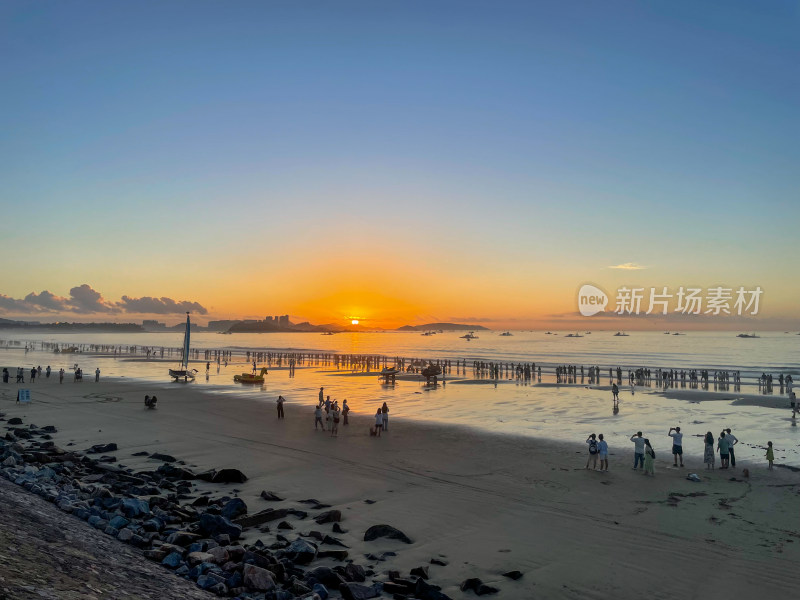 夕阳下热闹的海边沙滩景象