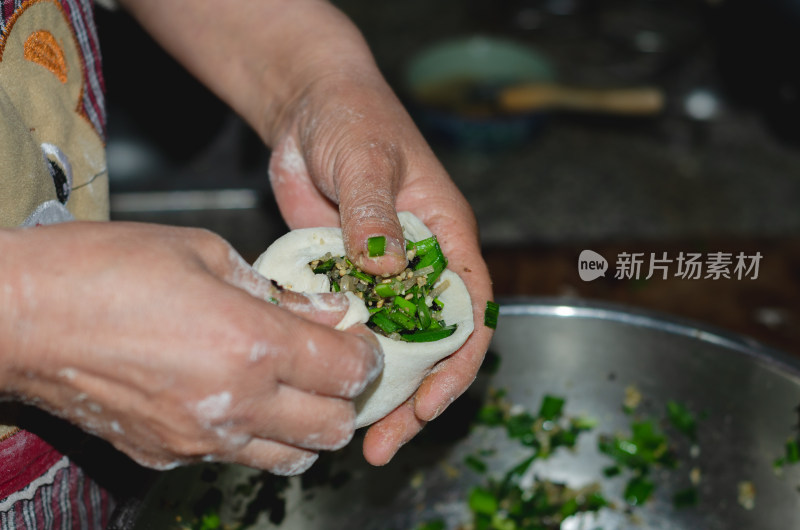 将馅料捏进包子皮里