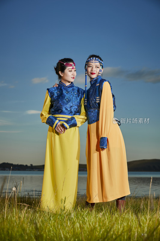 草原上穿着蒙古族传统服饰的年轻蒙族姐妹