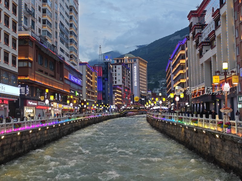 城市河道夜景，两岸霓虹映照湍急水流