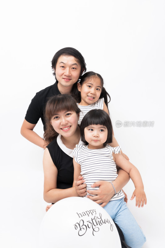 年轻的夫妻和两个女儿站在白色背景前
