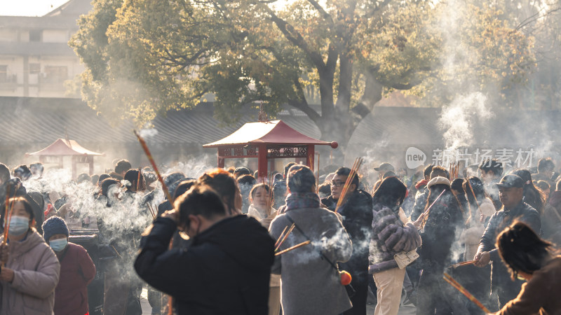 寺庙前众人手持香火烟雾缭绕的场景