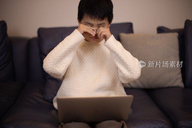 一个帅气的中国小男孩坐在沙发上看电脑
