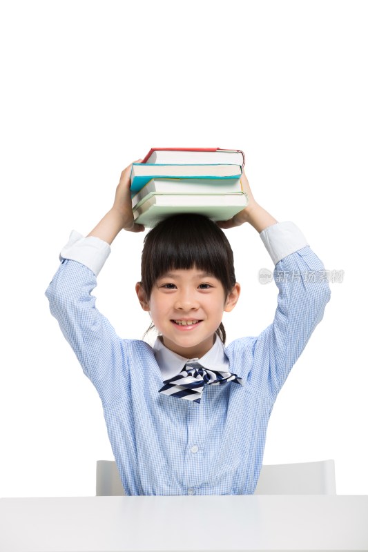 小女孩坐在课桌前头顶书本