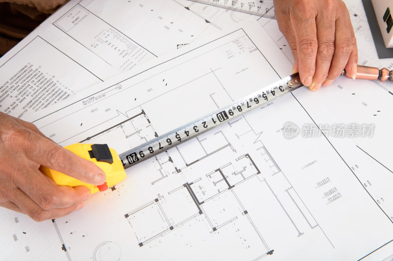 俯视拍摄建筑设计师使用卷尺测量图纸