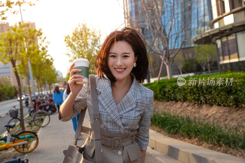 青年女人拿着饮料走在马路上