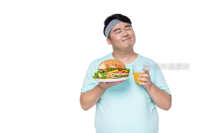 肥胖的年轻男子拿着汉堡和饮料