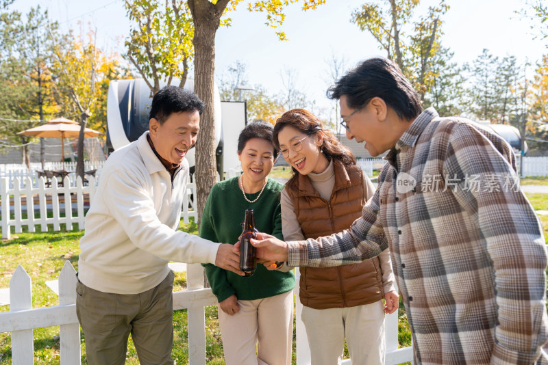 一群中老年人站在房车露营地喝啤酒