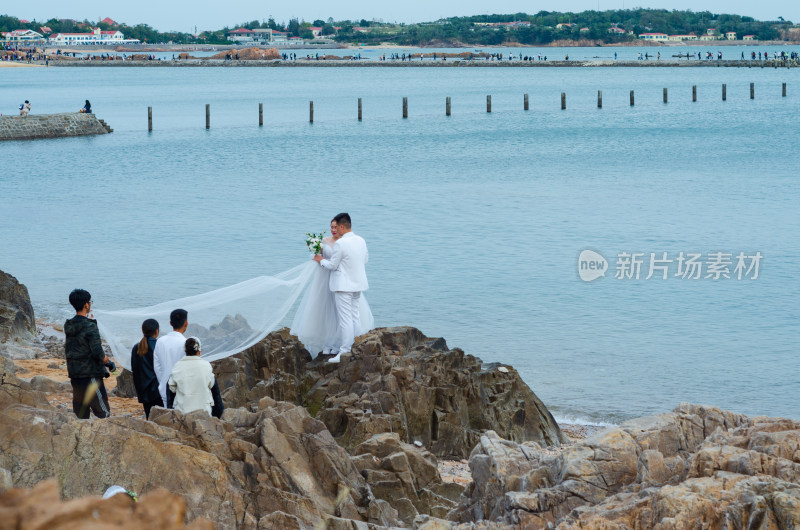 青岛海边礁石上，拍摄婚纱照的夫妻