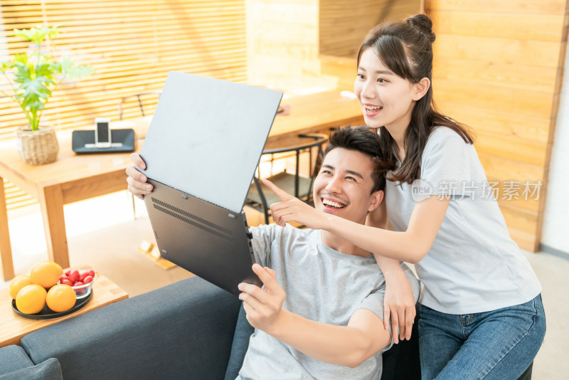年轻情侣在沙发上使用电脑