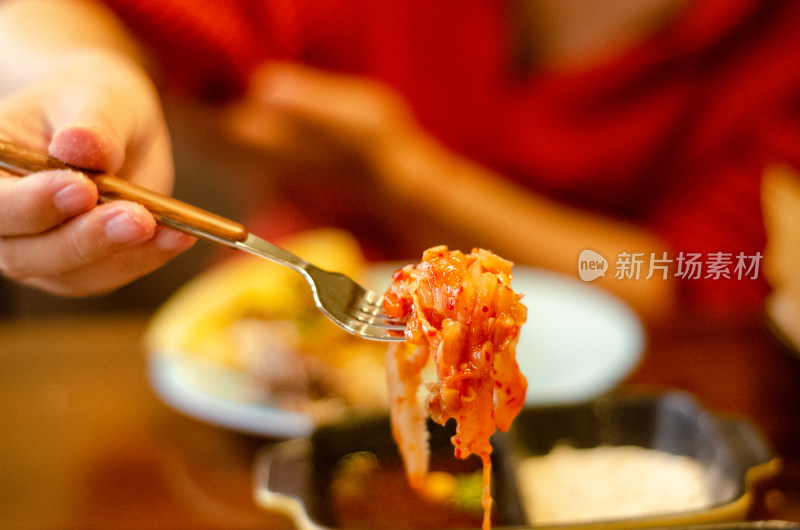 餐厅吃饭场景，用叉子挑起一块泡菜