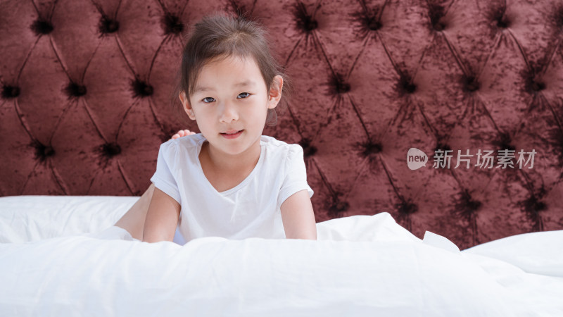穿着白色衣服在床上玩耍的中国女孩