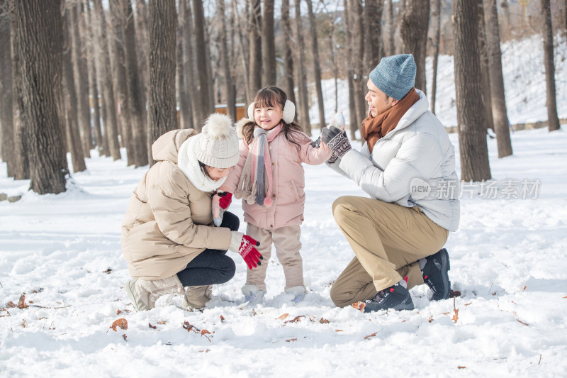 一家三口在雪地里玩耍