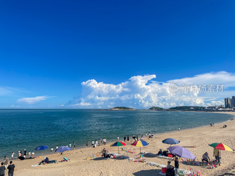 蓝天白云下热闹的海边沙滩场景