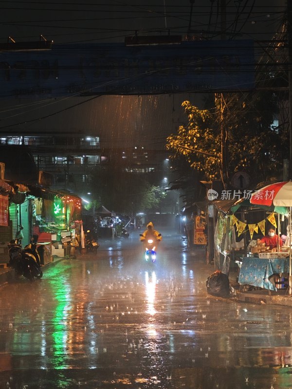 雨夜中骑摩托车行驶在街边的人