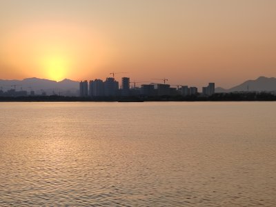 水边城市日落景象，阳光洒在城市建筑上