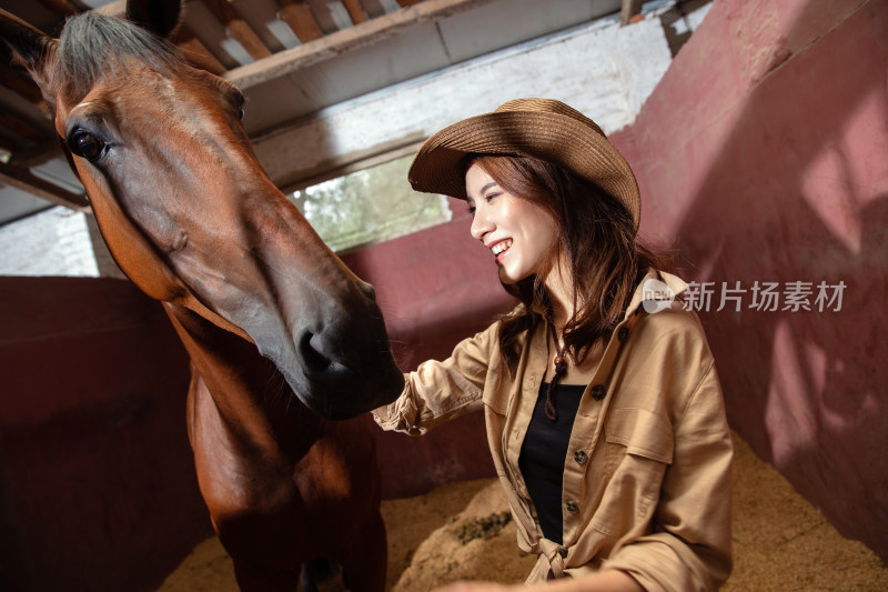 马厩里的快乐的青年女人和骏马