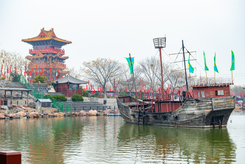 开封清明上河园古风建筑旁水面上的古船