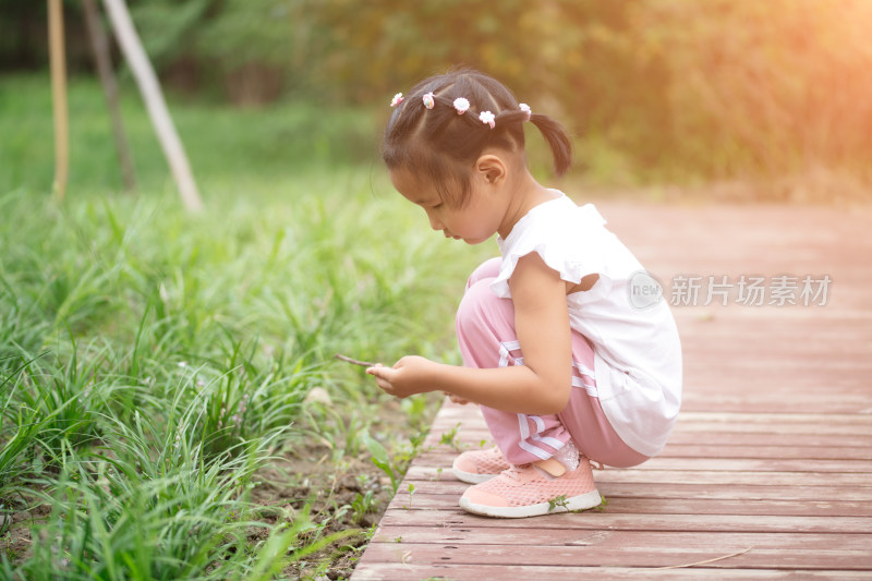 小姑娘蹲在公园小路边玩耍