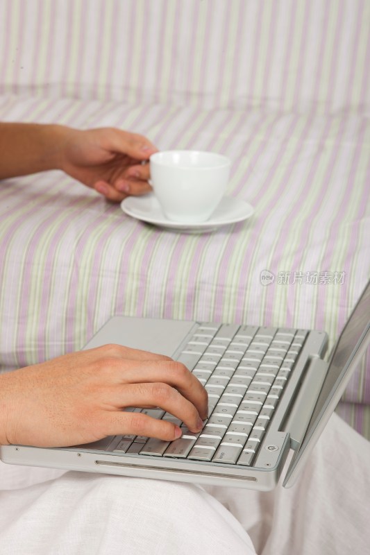 年轻男人边喝咖啡边使用笔记本电脑