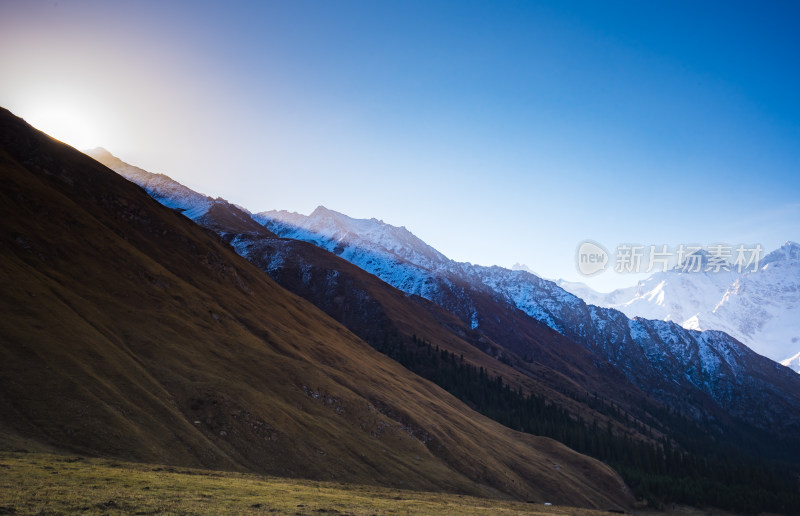 雪山清晨第一缕阳光照在金色的草地上