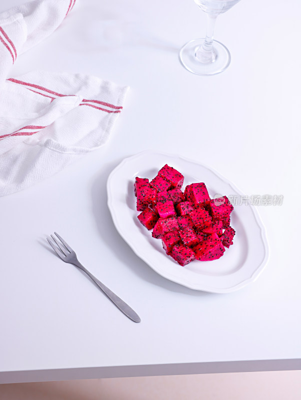 白色桌面上摆放着一碟子的水果火龙果果肉