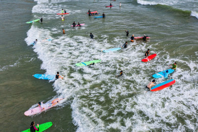 三亚市海棠区后海度假村游客正在海边冲浪