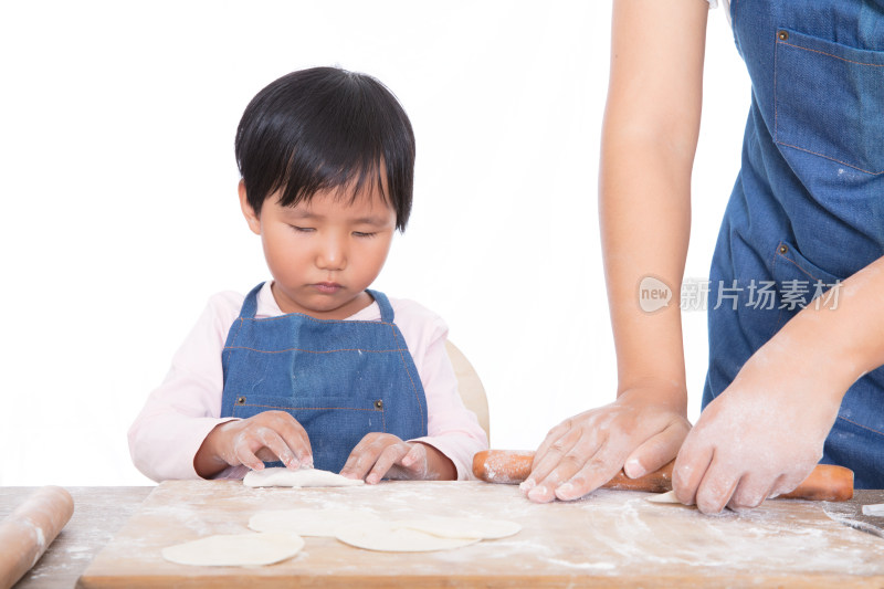 在妈妈旁边的小女孩认真的学习包饺子