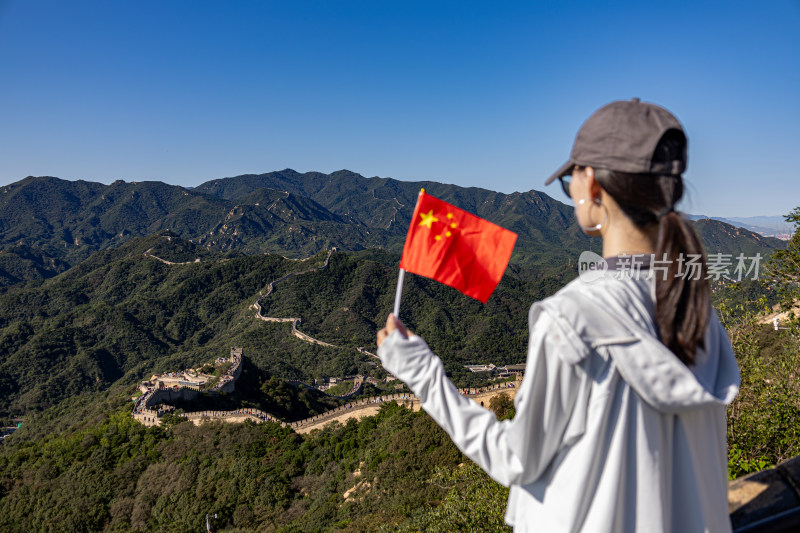 一个女人拿着国旗与八达岭长城合影