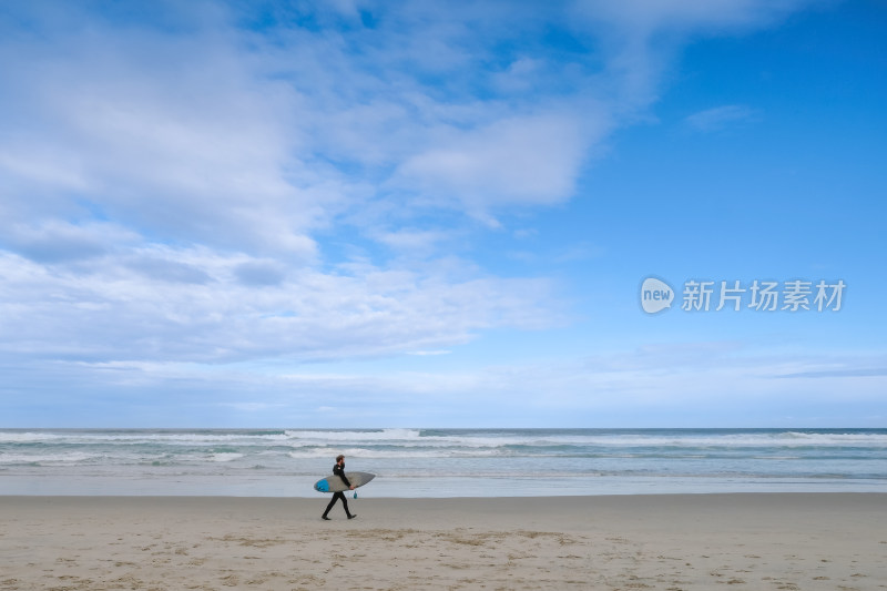 海滩上持冲浪板行走的人