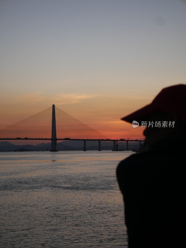 人物远眺夕阳下跨海大桥