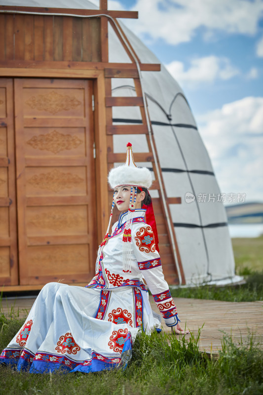 草原湖畔身穿蒙古族饰手持弓箭的蒙族少女