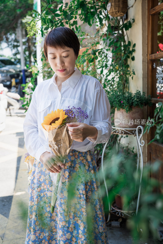 夏天站在花店门口拿着花束的中国女性