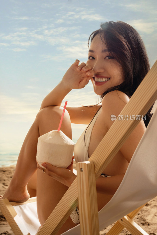 青年女孩在沙滩上喝椰汁