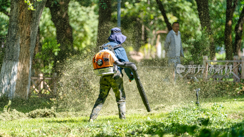 公园里的绿化工人正使用吹草机吹草地