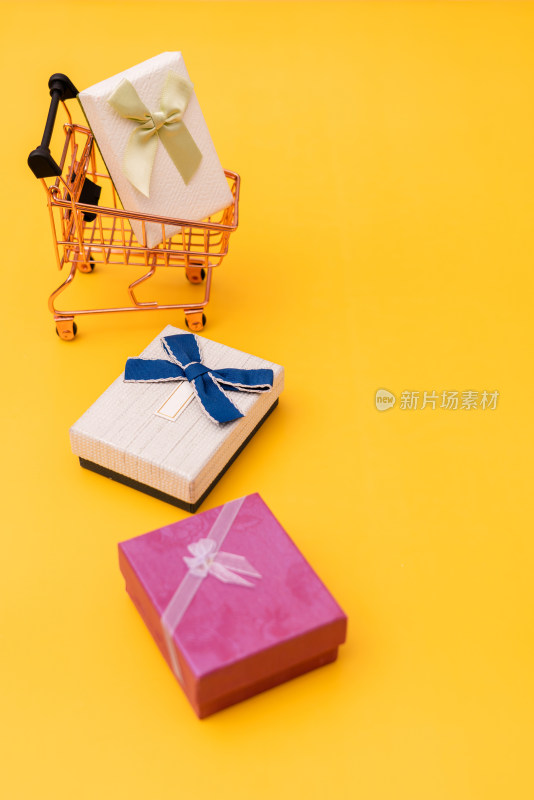 黄色背景上的购物车模型和礼品盒子