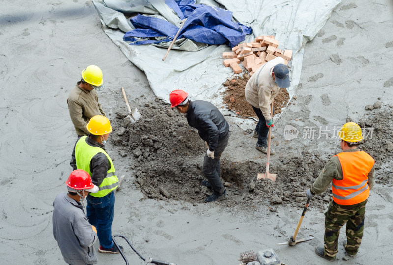 建筑工地上几个合作挖坑的建筑工人