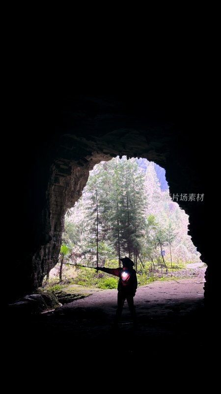 山洞洞口处探险者举灯探索的场景