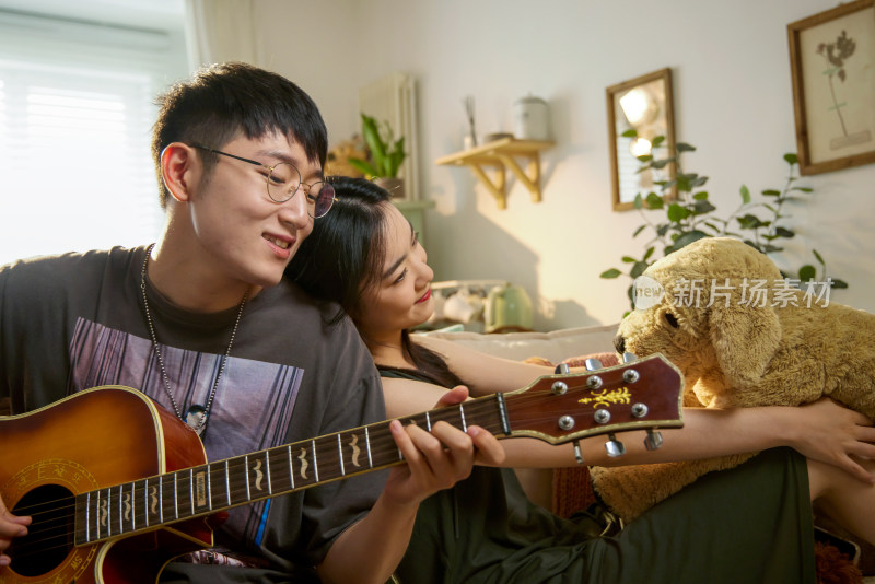 年轻情侣在家里弹吉他