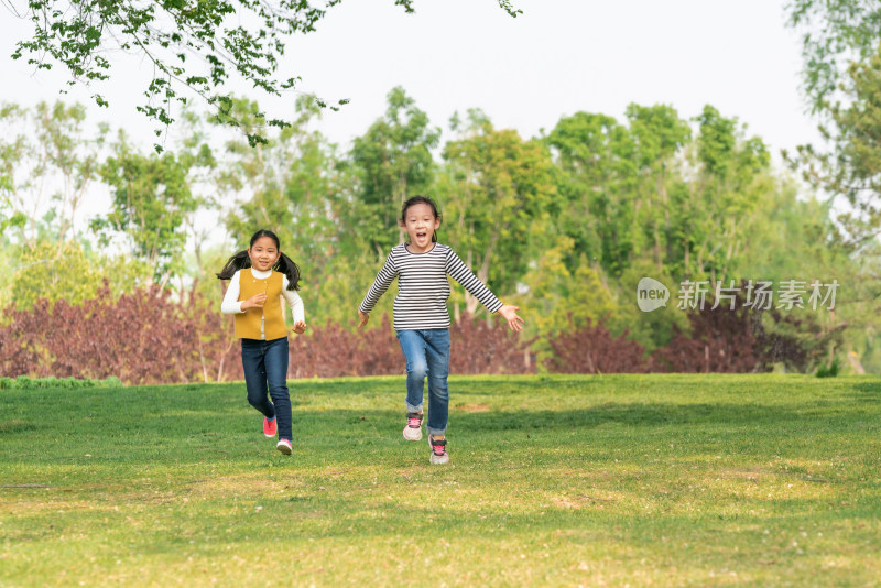 夏天两名牵手在公园草坪上奔跑中国女孩