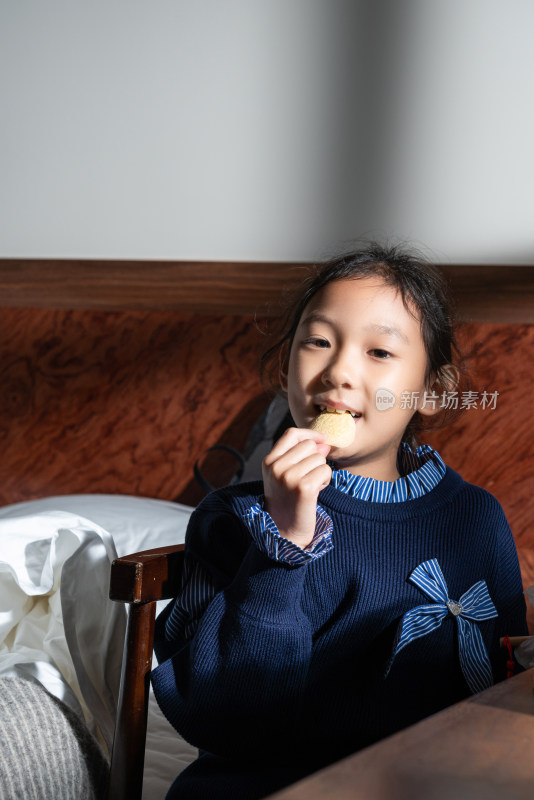 夕阳下坐在室内吃零食的中国女孩
