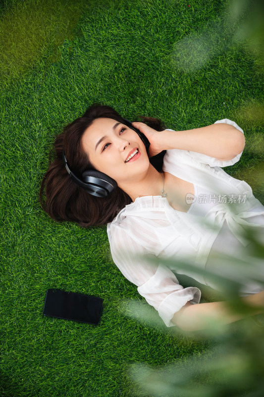 躺在草地上听音乐的青年女人