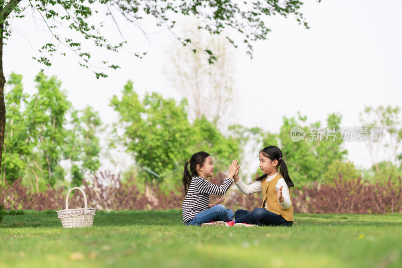 两个坐在树下玩拍手游戏的女孩